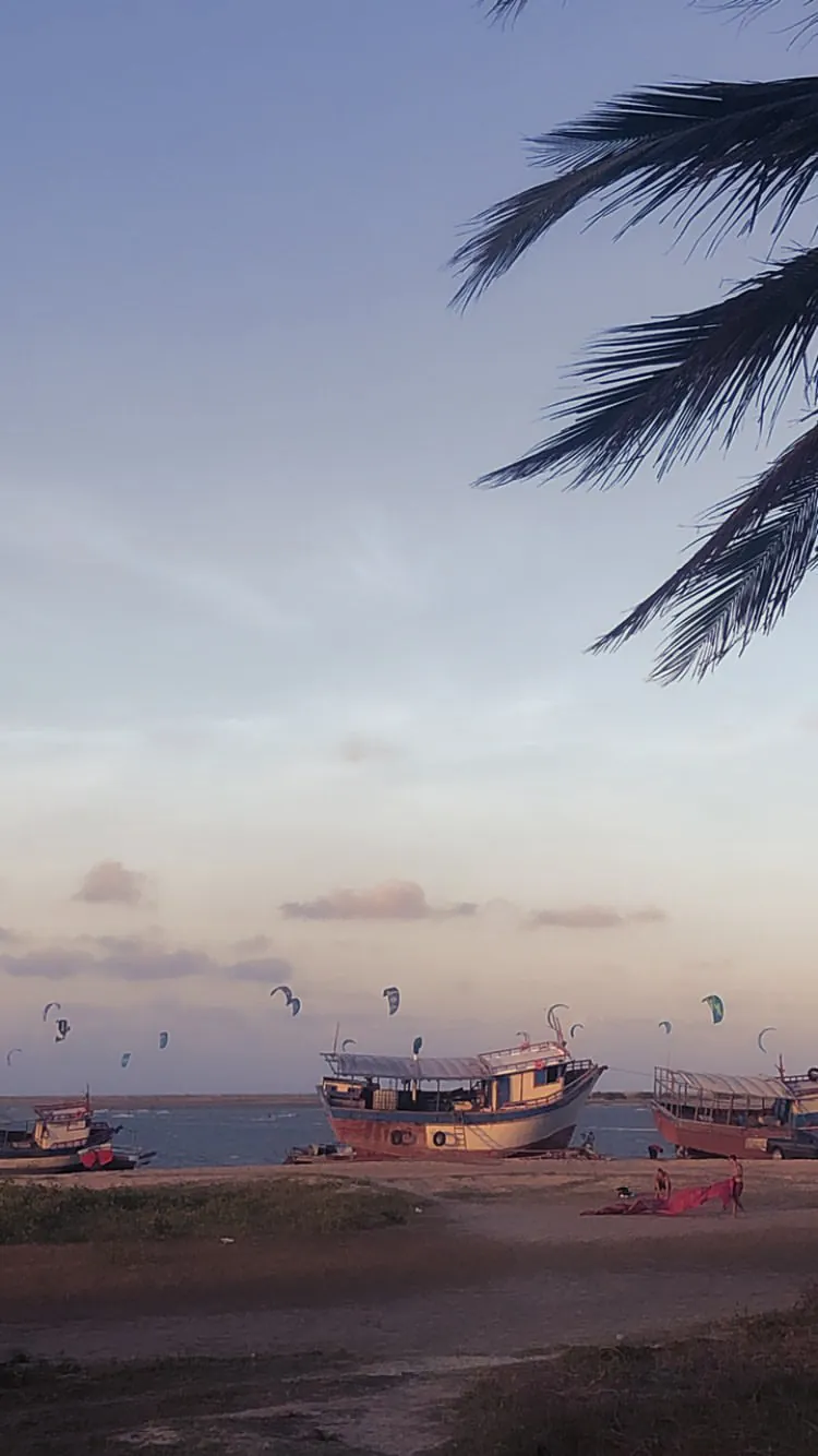 Kitesurfer riding on the flat water at Ilha do Guajirú with a fishing raft behind