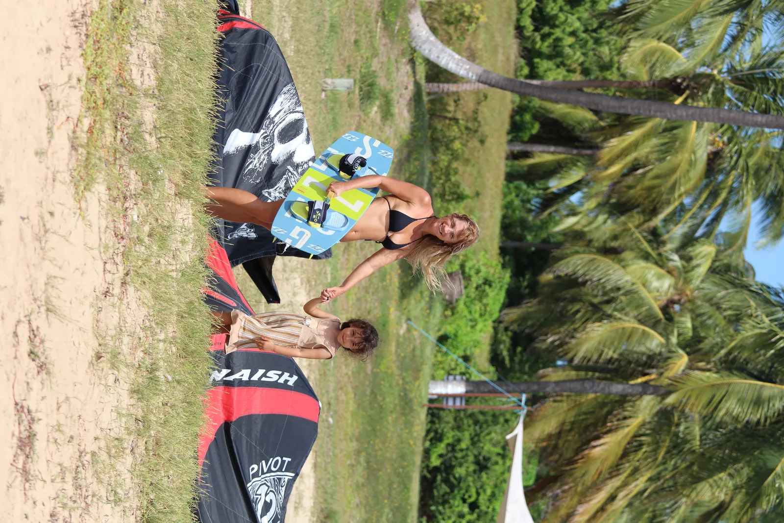 Equipamento de kitesurf Naish no chão com instrutores e alunos ao fundo na praia da Ilha do Guajirú
