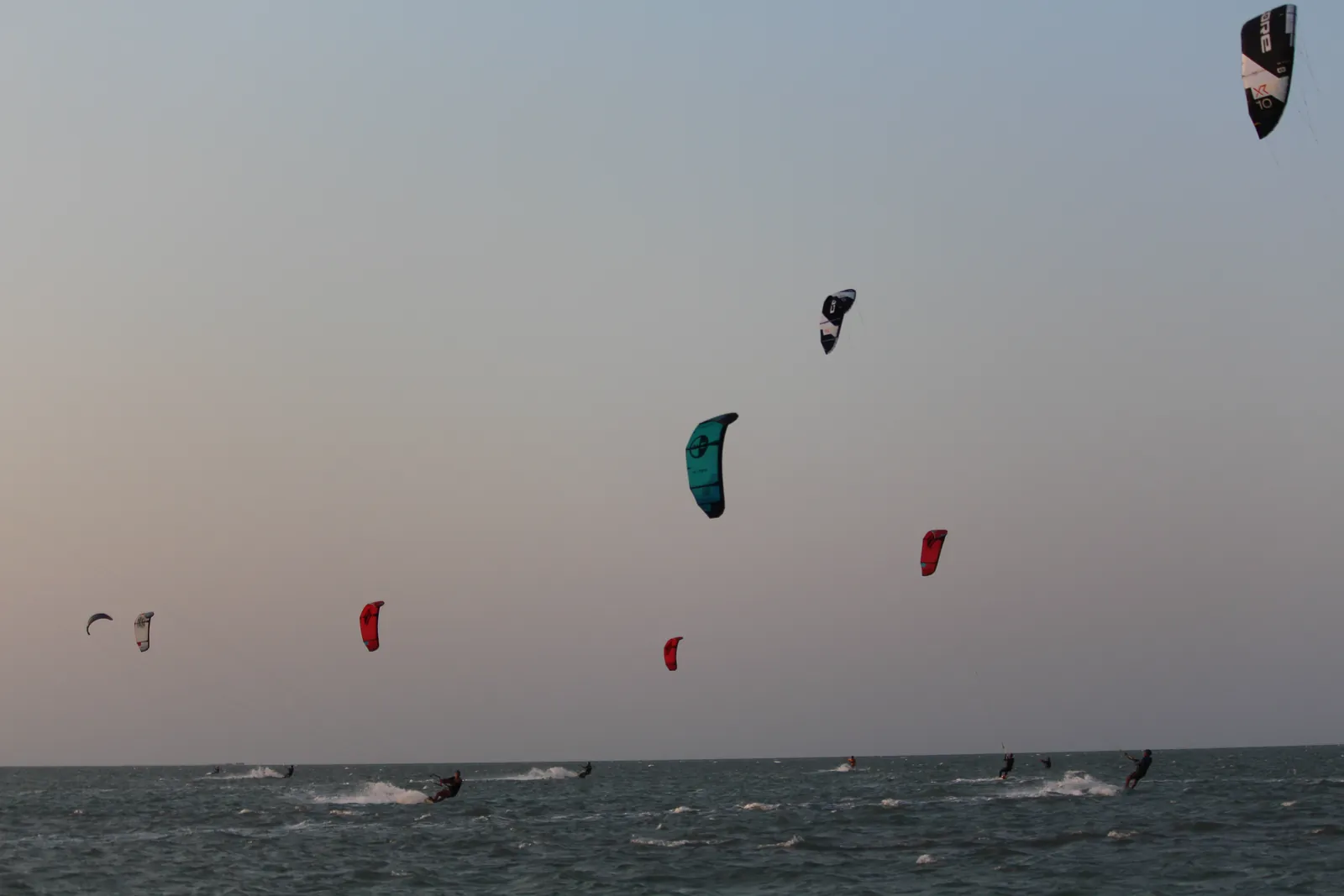 Pipas coloridas voando sobre o horizonte do mar em luz dourada de entardecer na Ilha do Guajirú