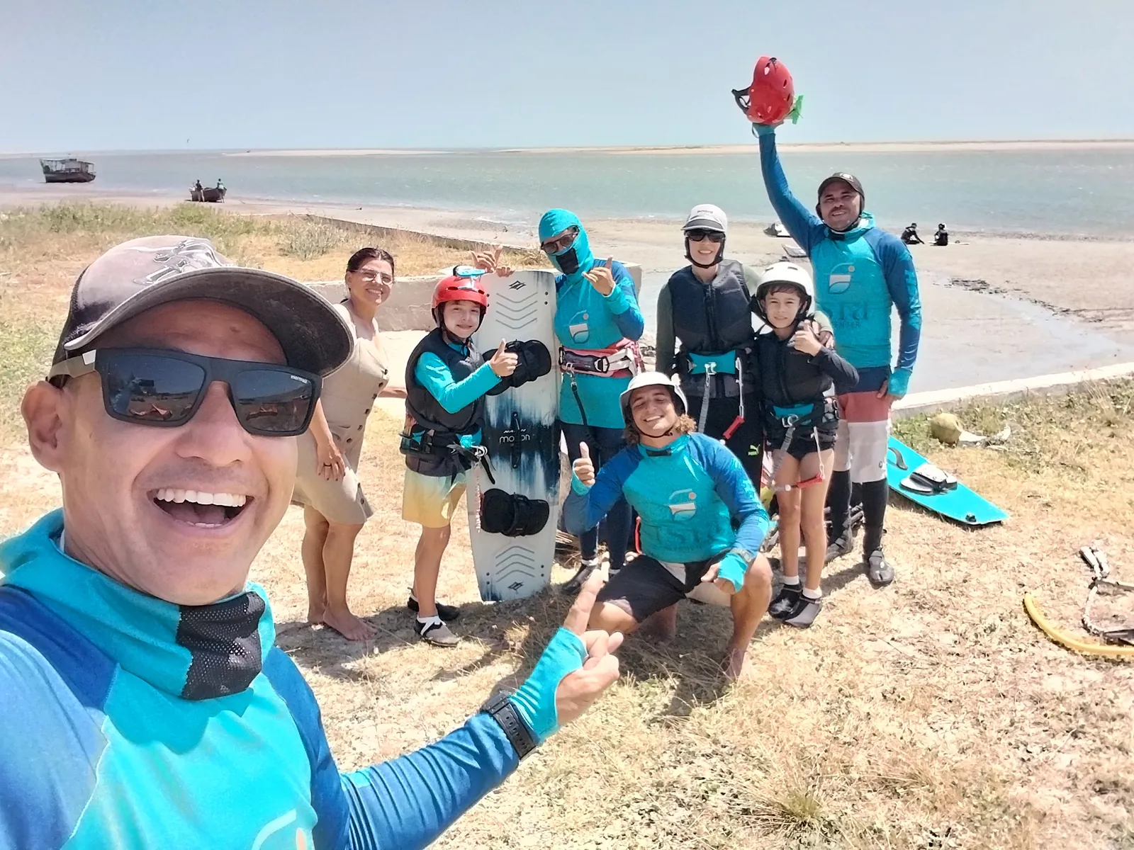Instrutor do Isla Kite Center com óculos de sol sorrindo em selfie na praia com grupo de alunos com equipamento de kitesurf ao fundo na Ilha do Guajirú