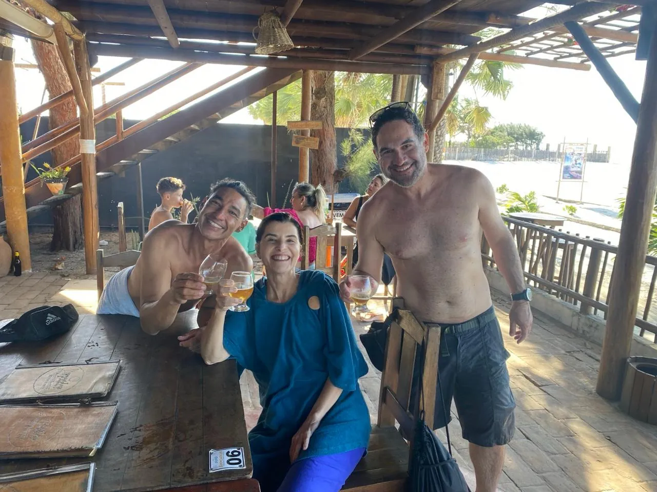 Grupo de alunos e instrutores do Isla Kite Center brindando e sorrindo em área de bar da escola na Ilha do Guajirú