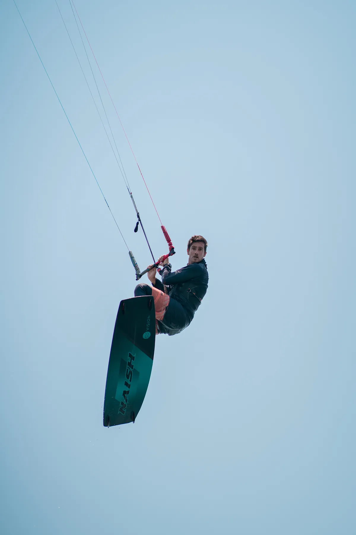 Kitesurfista executando salto aéreo com kite Naish sobre a água plana da Ilha do Guajirú