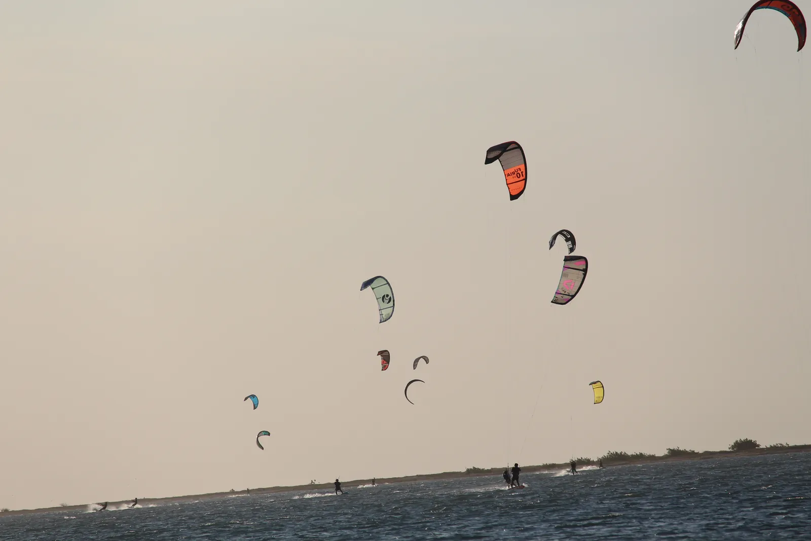 Colorful kites above the shallow sea channel at Ilha do Guajirú at dusk